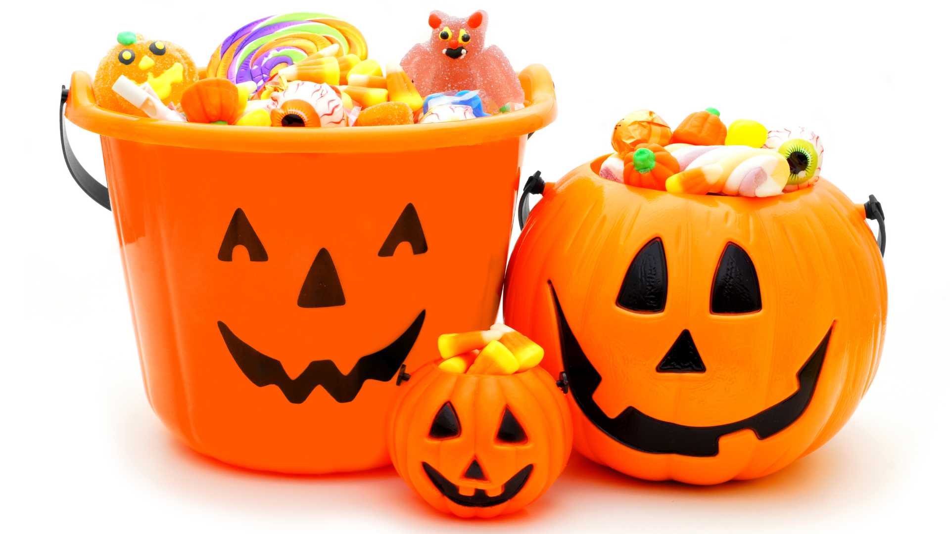 Halloween with autism: Halloween and autism: Three smiling plastic jack-o’-lantern containers, one in the shape of a bucket, the next circular, and the other small, filled to the brim with toys and candy.